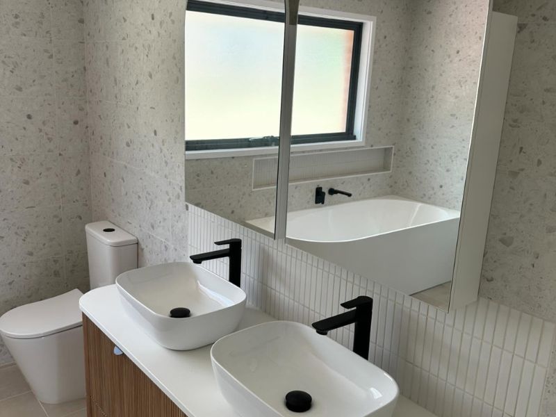 Freestanding bathtub and timber vanity in a luxury spa-inspired ensuite bathroom in Sydney.