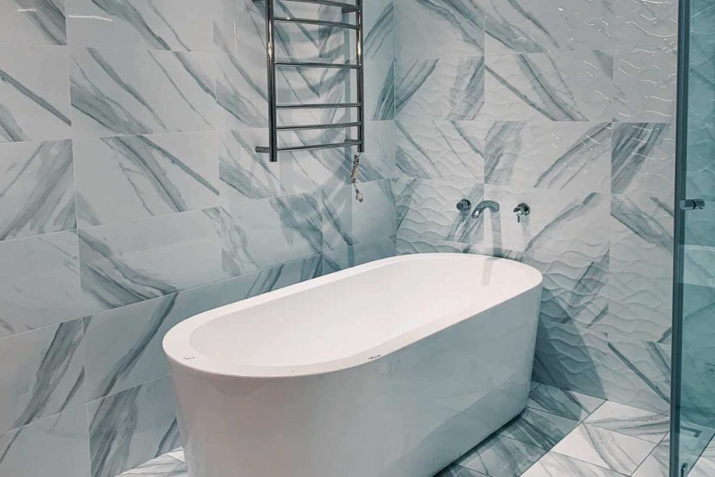Luxurious marble look tiled bathroom with freestanding bathtub and towel rail, completed by Empire Tiles in Sydney