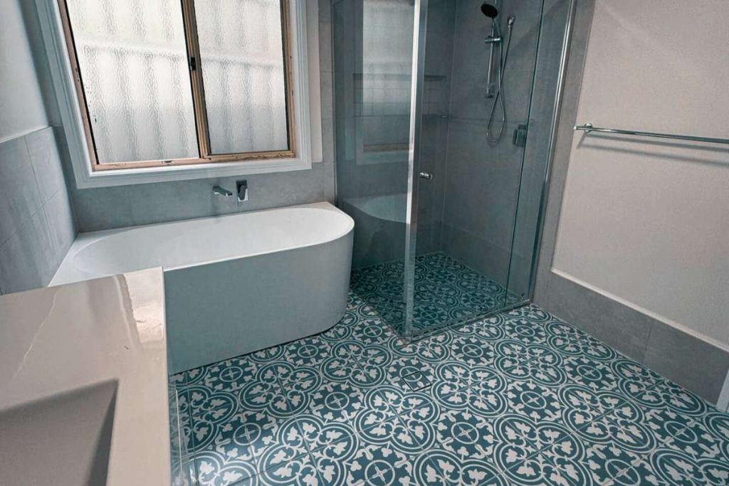 Heritage inspired Sydney bathroom featuring freestanding tub, frameless glass shower, and blue patterned floor tiles renovation by Empire Tiles
