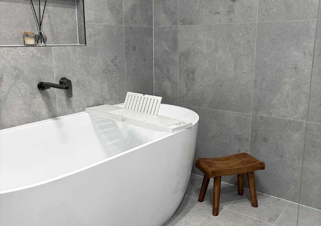 Elegant freestanding tub against grey porcelain tiles in a moisture-resistant Sydney bathroom—renovation by Empire Tiles to prevent leaks and mould buildup
